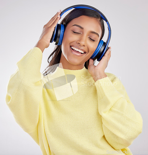 Image of Woman with headphones, listening to music and happy on studio background with freedom, fun and peace. Smile, carefree and technology with entertainment, Indian female and radio streaming playlist