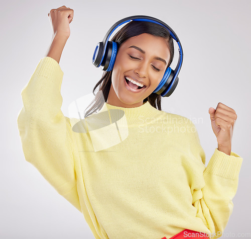 Image of Woman with headphones, listen to music and happy on studio background with freedom, fun and peace. Smile, carefree and technology with entertainment, Indian female and radio streaming playlist