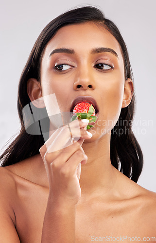 Image of Eating strawberry, studio or healthy Indian woman with skincare beauty or wellness in headshot. Food nutrition, bite or face of girl model with vitamin c or red fruits isolated on a white background