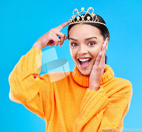 Image of Pointing, crown and portrait of woman in studio for celebration, princess or wow party. Smile, beauty or fashion with female tiara on blue background excited for achievement, winner and prom surprise