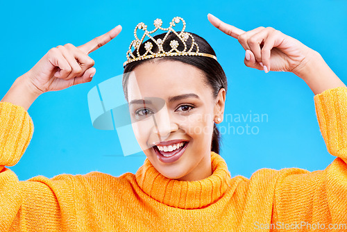 Image of Point, crown or portrait of woman in studio celebration, princess and birthday party. Smile, beauty and fashion with female tiara on blue background and excited for achievement, winner and prom event
