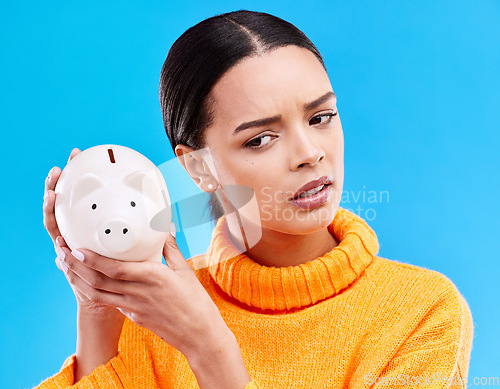 Image of Piggy bank, investment and woman in a studio saving her money for financial growth or profit. Banking, budget and female model with a cash investing plan with finance knowledge by a blue background.