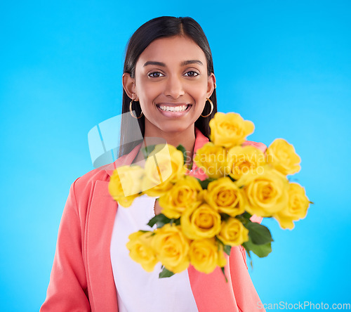 Image of Happy, gift and a portrait of a woman with flowers isolated on a blue background in a studio. Smile, holding and a girl giving a floral bouquet as a present, showing a flower and fresh roses