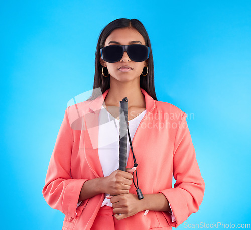 Image of Blind, face and woman with disability in a studio with guide cane for eyes impairment help. Glasses, serious or young female person in post eye surgery on isolated blue background with vision problem