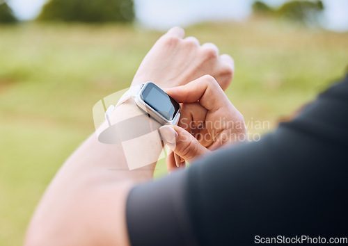 Image of Hands, training and smart watch with a sports person outdoor, checking the time during a workout. Arm, exercise and technology with an athlete tracking cardio or endurance performance for fitness