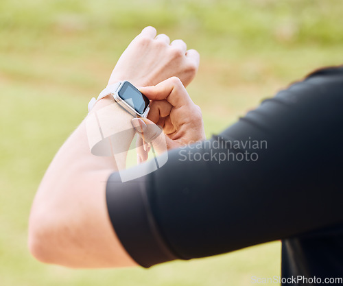 Image of Hands, fitness and smart watch with a sports person outdoor, checking the time during a workout. Arm, exercise and technology with an athlete tracking cardio or endurance performance while training