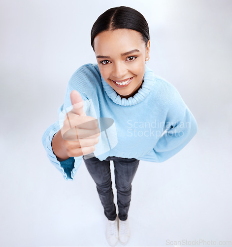 Image of Portrait, thumbs up and above with a woman on a white background in studio for motivation or success. Winner, emoji and hand gesture with an attractive young female saying thank you to show support
