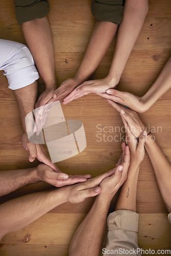 Image of Hands, teamwork and circle with business people on a wooden table in the office closeup from above. Collaboration, synergy and an employee group or team together in a huddle during a meeting at work