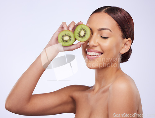 Image of Happy, skincare and kiwi with woman in studio for natural cosmetics, diet and nutrition. Product, glow and self care with female model and fruit on white background for spa, food and vitamin