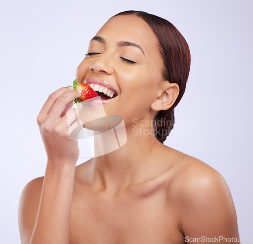 Image of Woman, skincare and studio for eating strawberry with self care, diet and beauty with benefits for glow on face. Girl, model and fruit for nutrition with wellness, health or dermatology by background