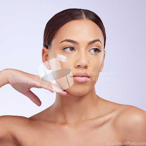 Image of Woman, skincare cream and thinking in studio for self care, aesthetic or beauty with product application on face. Girl, model and facial skin wellness with cosmetic, health or dermatology by backdrop