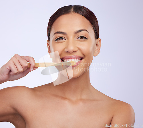 Image of Portrait, dental or happy girl brushing teeth with smile for healthy oral hygiene in studio white background. Beauty or Brazilian woman model cleaning mouth with a natural bamboo wooden toothbrush