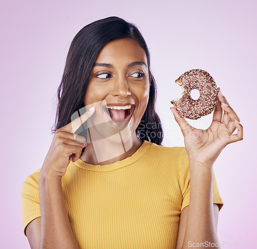 Image of Donut, dessert and bite with woman in studio for diet, snack and happiness. Sugar, food and smile with female eating sweets treat isolated on pink background for nutrition, excited and craving mockup