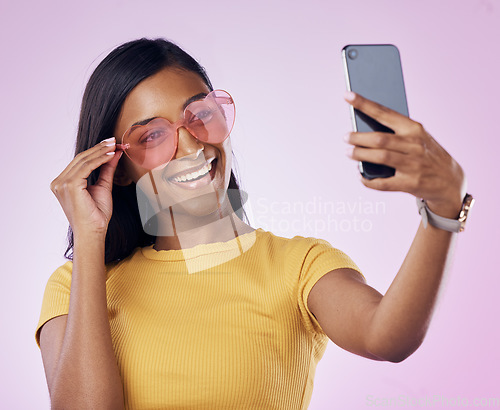 Image of Sunglasses, selfie and happy Indian woman on pink background with cosmetics, confidence and beauty. Fashion, summer style and girl in studio take picture for social media, post and influencer blog