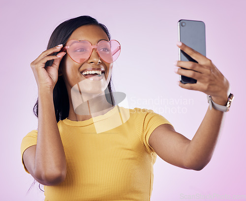 Image of Sunglasses, selfie smile and Indian woman on pink background with cosmetics, confidence and beauty. Fashion and girl in studio take picture for social media, post and influencer blog