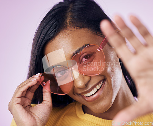 Image of Heart, sunglasses and indian woman selfie in studio happy, cheerful and fun on purple background. Glasses, portrait and female gen z fashion influencer smile for profile picture, photo or blog post