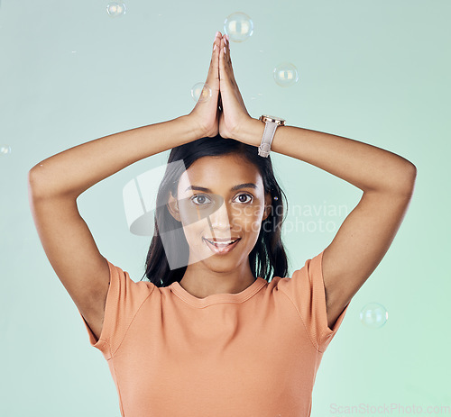 Image of Portrait, yoga and bubbles with a woman meditating in studio on a gray background for zen or namaste. Fitness, health and wellness with an attractive young female yogi practicing meditation for peace