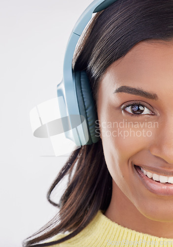 Image of Portrait, headphones and half with a woman in studio on a gray background listening to music. Face, happy and smile with an attractive young female streaming audio using a subscription service