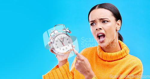 Image of Frustrated, time and woman with an alarm clock, late and angry against a blue studio background. Female, shouting and person pointing to watch, screaming and schedule with appointment or disagreement