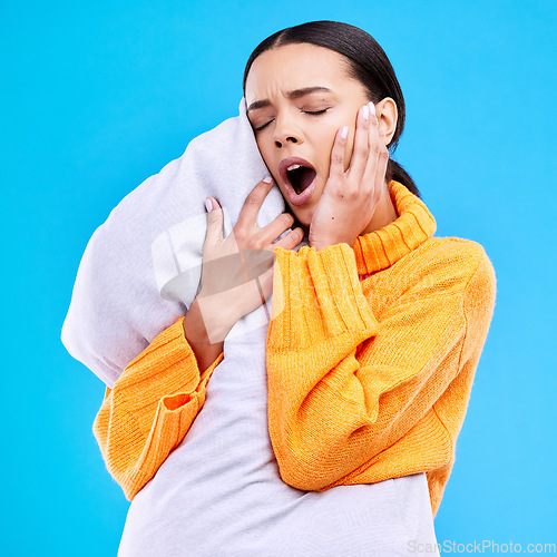 Image of Tired woman, pillow and yawn in studio with exhausted face, and ready to sleep by blue background. Girl, model and open mouth for sleeping, rest or nap for self care, mental health and peace of mind