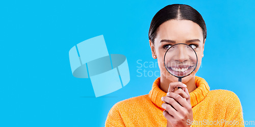 Image of Happy, smile and woman with magnifying glass in studio for zoom on her mouth for dental health. Happiness, excited and female model from Brazil with magnifier isolated by blue background with mockup.