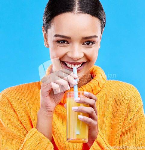 Image of Happy woman, portrait and straw for drinking orange juice in studio, blue background and smile. Female model, glass and sip of fruit cocktail for nutrition, vitamin c diet and detox vegan smoothie