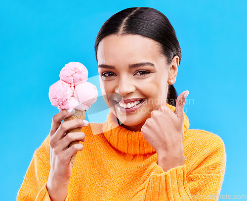 Image of Woman, studio portrait and ice cream with thumbs up, smile and happiness by blue background. Girl, model and sweet dessert with hand sign, happy and excited for food, gelato and eating by backdrop