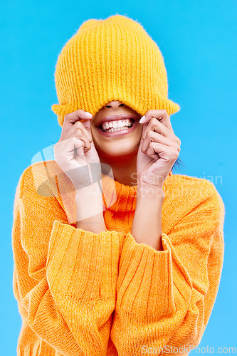 Image of Fashion, crazy and cover with woman and beanie in studio for hiding, winter and goofy. Playful, happiness and smile with female and knitted hat isolated on blue background for funny, silly and cool