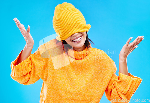 Image of Fashion, crazy and cover with woman and beanie in studio for hiding, winter and goofy. Playful, happiness and smile with female and knitted hat isolated on blue background for funny, silly and cool