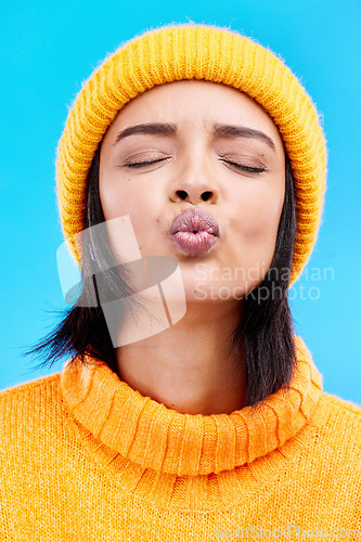 Image of Portrait of woman in winter fashion with kiss face, beanie and jersey isolated on blue background. Style, flirt and romance, gen z girl in studio backdrop with love and warm clothing for cold weather