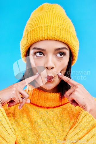 Image of Goofy woman in winter fashion with comic expression, beanie and fun isolated on blue background. Style, happiness and silly gen z girl in studio with funny face and warm clothing for cold weather.