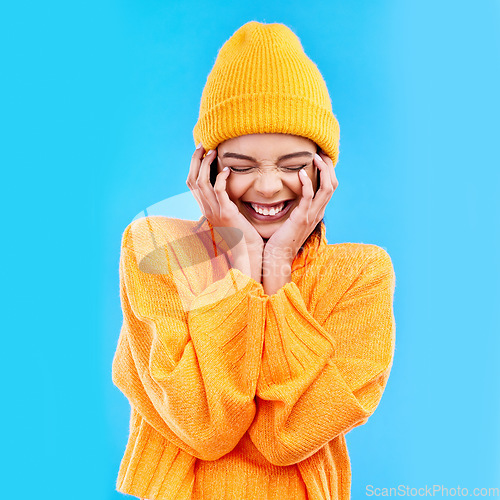 Image of Happiness, excited and woman with youth in studio ready for cold weather with winter hat. Isolated, blue background and smiling with a happy young and gen z person with a smile, beanie and joy