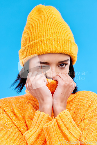 Image of Portrait of woman in winter fashion with cozy jersey, beanie and wink isolated on blue background. Style, happiness and gen z girl in studio backdrop with mock up and warm clothing for cold weather.