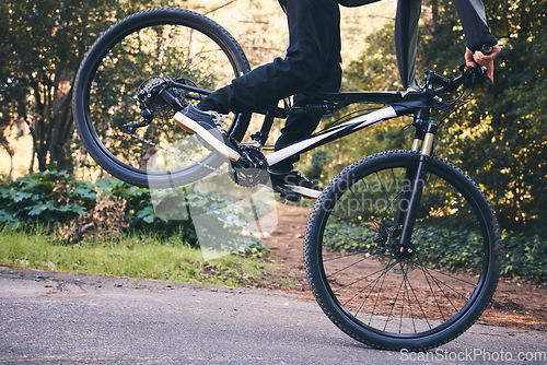 Image of Closeup man, mountain bike and wheel for cycling stunt in park, nature and path for fitness, cardio and freedom. Bicycle, cyclist and extreme sports athlete training for action, wheelie stunt or risk