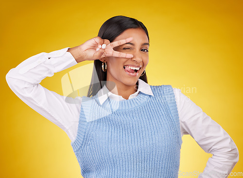 Image of Peace sign, hands and portrait of Indian woman wink in studio for happiness, confident and fashion. Emoji mockup, yellow background and girl with hand gesture for joy, positive mindset and happy