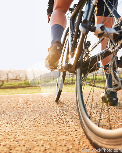 Image of Bicycle closeup, countryside ride and person on a bike with speed for sports race on a gravel road. Fitness, exercise and athlete legs doing sport training in nature on a trail for cardio and workout