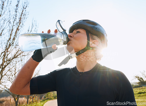 Image of Woman drinking water, bottle and cycling with fitness outdoor, helmet for safety and health with hydration. Athlete, biking and female with healthy and active lifestyle, wellness and sports training