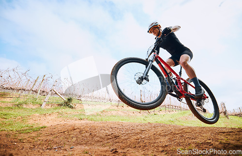 Image of Bicycle jump, countryside and woman on a bike with speed for sports on a dirt road. Fitness, exercise and fast athlete doing sport training in nature on a park trail for cardio and cycling workout