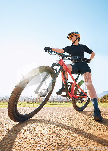 Image of Bicycle break, ride and woman on a bike from below for sports race on a gravel road. Fitness, exercise and athlete doing sport training in nature or countryside for cardio rest and healthy workout