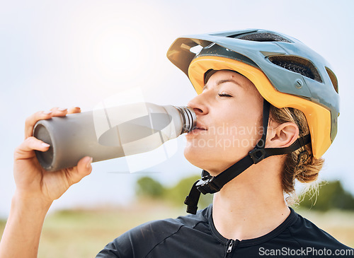 Image of Woman drinking water, bottle and cycling with exercise outdoor, helmet for safety and health with hydration. Athlete, biking and female with healthy and active lifestyle, fitness and sports training