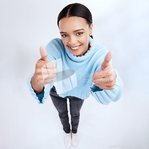 Image of Thumbs up, portrait and top view of happy woman in white background, winner and isolated studio. Female model, thumb and smile to celebrate winning achievement, like emoji and yes feedback of support