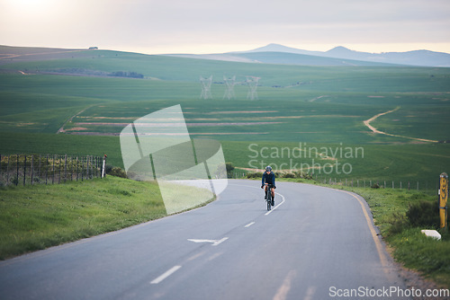 Image of Fitness, nature and cyclist cycling on a mountain while training for a race, competition or marathon. Sports, health and athlete doing a cardio exercise or workout with bicycle in the road on a hill.