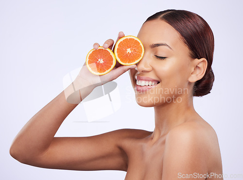 Image of Skincare, orange and woman in studio for vitamin c, treatment and cosmetics on purple background. Smile, fruit and girl model relax with diy facial, organic and skin, beauty and citrus cleaning