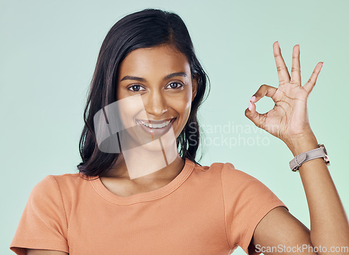 Image of Portrait, perfect hand gesture and woman in a studio with a positive, confident and happy mindset. Happiness, smile and young Indian female model with a ok sign language isolated by green background.