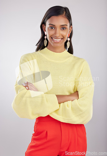 Image of Fashion, portrait and female with crossed arms in a studio with a stylish, trendy and classy outfit. Smile, happy and young Indian woman model with style and confidence isolated by a gray background.