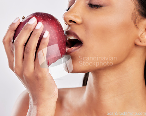 Image of Bite, apple or healthy Indian woman with skincare beauty or wellness in studio on white background. Food nutrition, eyes closed or face of girl model eating red fruits to promote vitamin c or diet