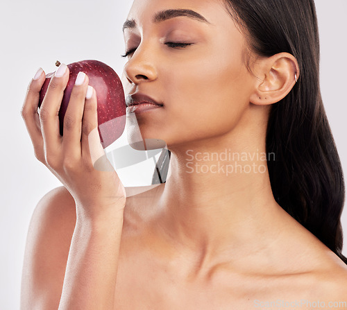 Image of Eating, apple or healthy Indian woman with skincare beauty or wellness in studio on white background. Food nutrition, eyes closed or face of girl model with red fruits to promote vitamin c or diet