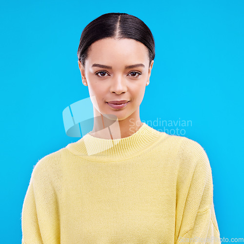 Image of Portrait, serious and woman in studio, relaxed and confident against a blue background. Face, pose and young female smile, relax and standing on isolated space, mockup and indoor product placement