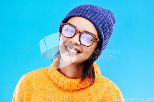 Image of Portrait of happy woman in winter fashion with glasses, beanie and smile isolated on blue background. Style, happiness and face of gen z girl on studio backdrop with warm clothing for cold weather.