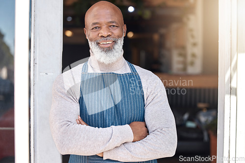Image of Black man, portrait smile and arms crossed in small business cafe or retail store by entrance door. Happy African American senior businessman standing in confidence at restaurant or coffee shop